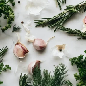 Fresh herbs and garlic arranged on a clean white background, showcasing their vibrant colors and textures