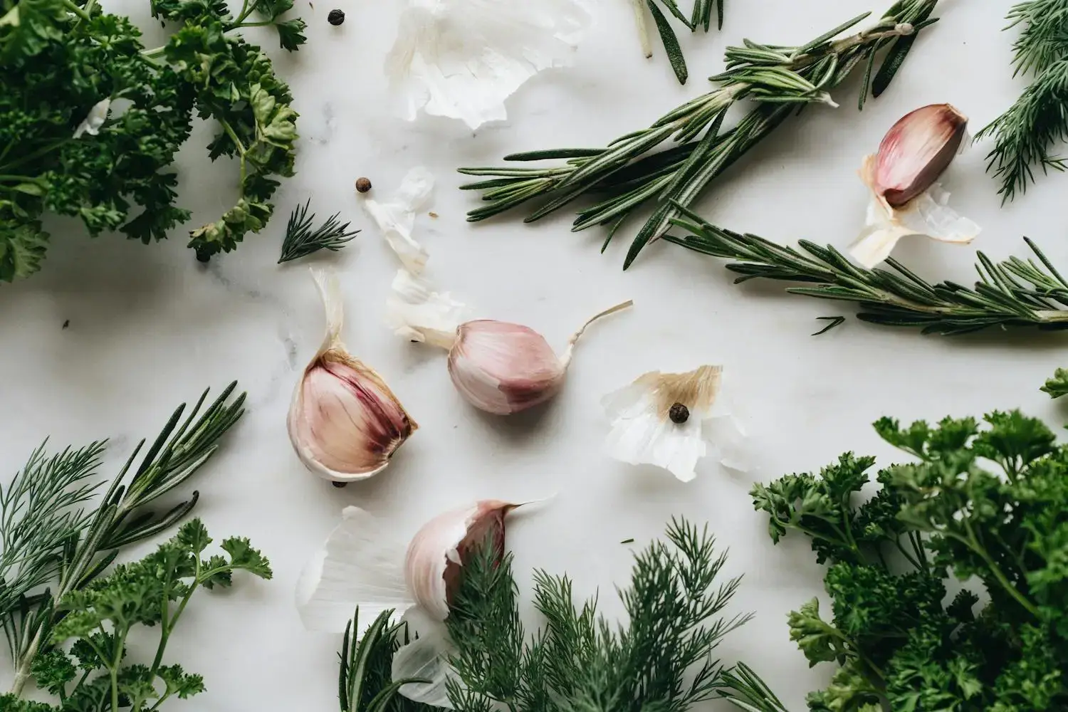Fresh herbs and garlic arranged on a clean white background, showcasing their vibrant colors and textures